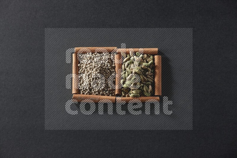 2 squares of cinnamon sticks full of white peppers and cardamom on black flooring