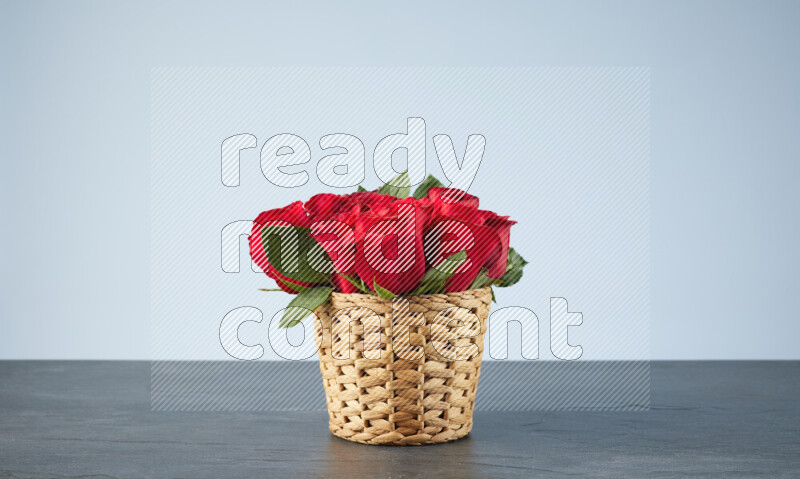 Vibrant red roses in a wicker basket on black marble background