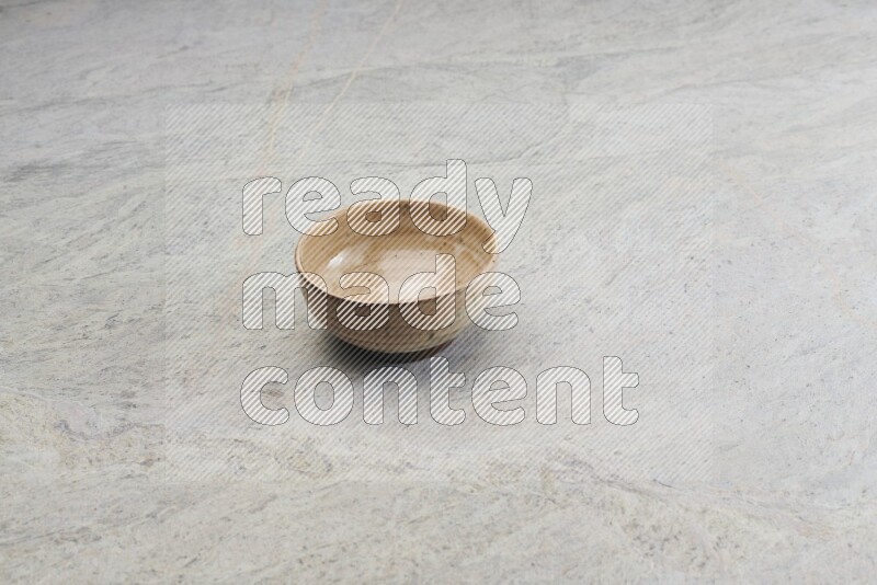 A small beige pottery bowl on grey marble background