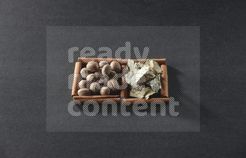 2 squares of cinnamon sticks full of nutmegs and bay laurel leaves on black flooring