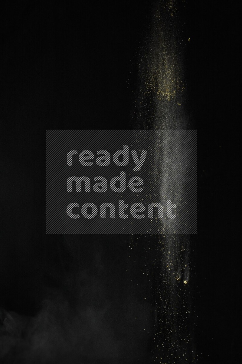 A side view of yellow powder explosion on black background