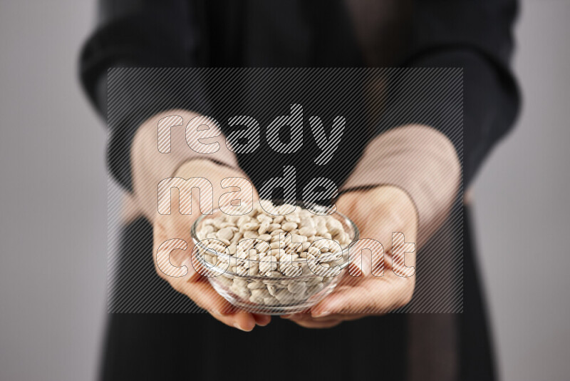 Woman in abaya holding different kinds of legumes in different positions