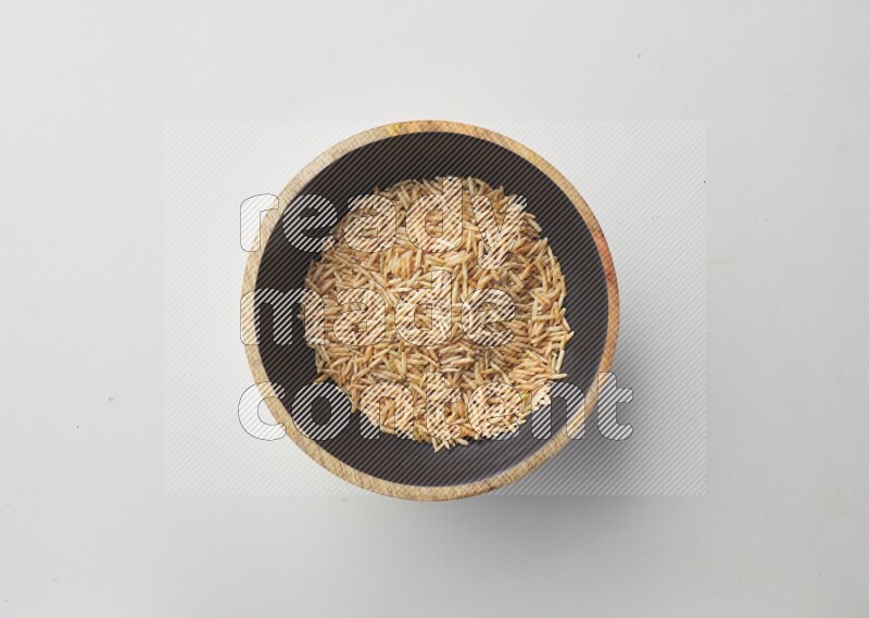 Top-view shot of long grain brown rice in a container on white background