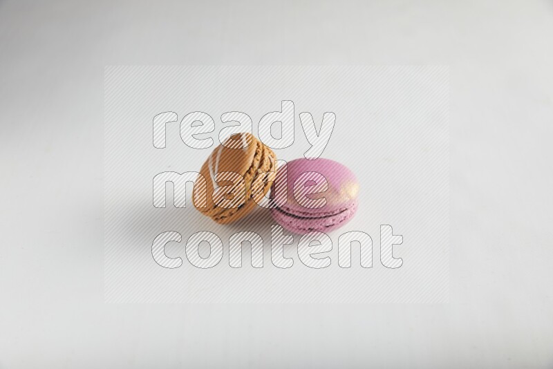 45º Shot of of two assorted Brown Irish Cream, and Purple Strawberry macarons on white background