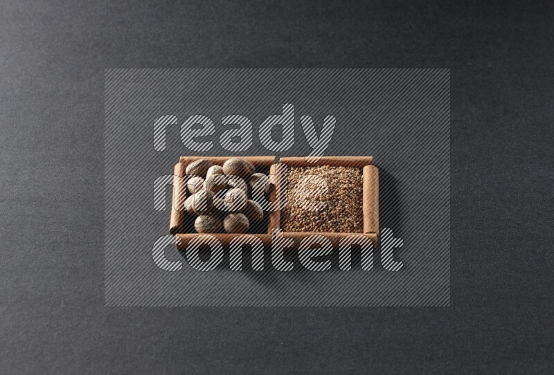 مربعان من أعواد القرفة ممتلئان بحبوب الخردل وجوزة الطيب علي خلفية سوداء