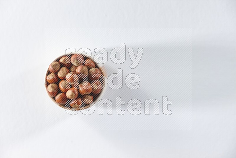 A beige ceramic bowl full of hazelnuts on a white background in different angles