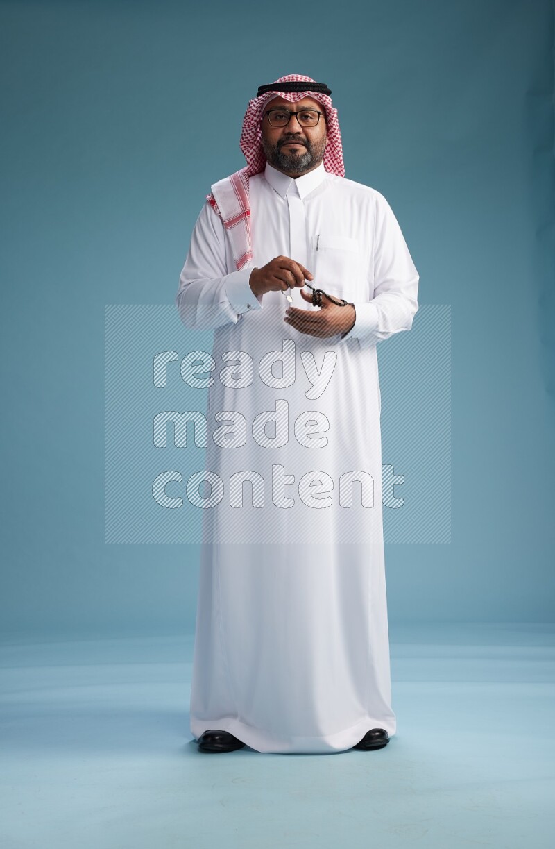 Saudi Man with shimag Standing Interacting with the camera on blue background