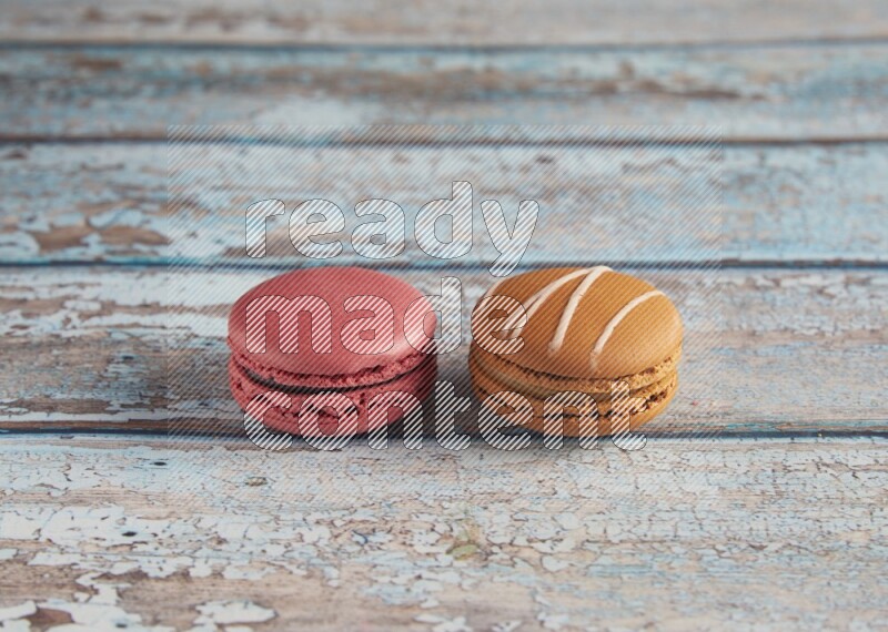 45º Shot of of two assorted Brown Irish Cream, and Pink Raspberry macarons on light blue background