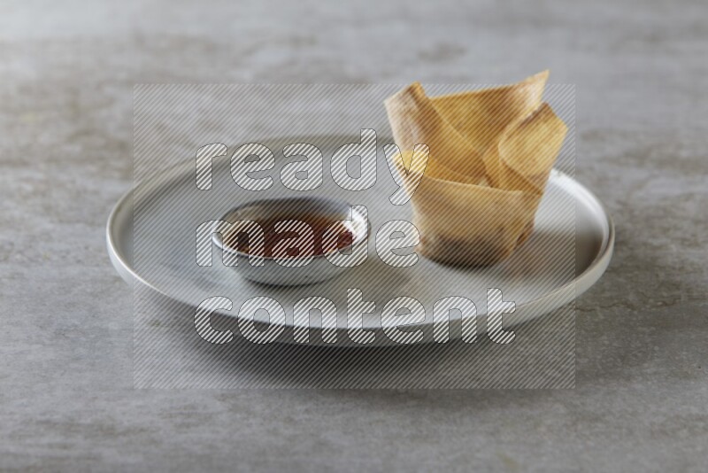wonton cups with soy sauce ramkin on grey ceramic plate on grey textured counter top