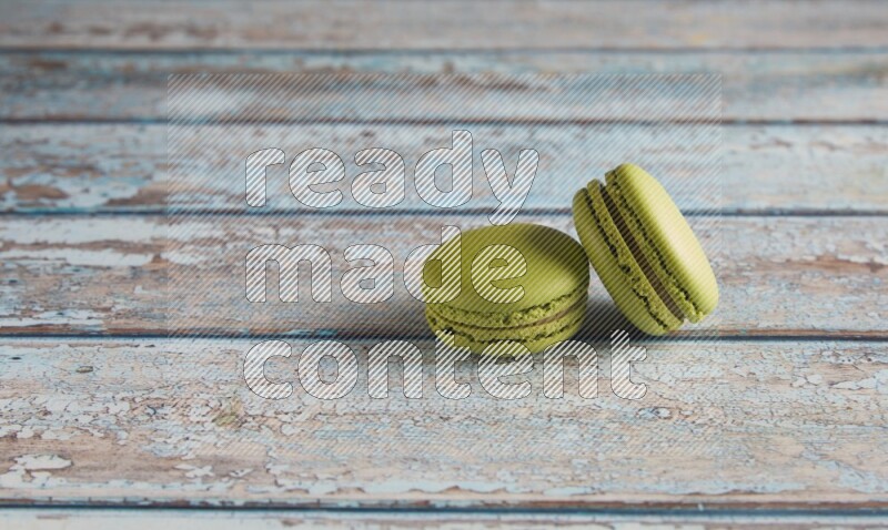 45º Shot of two Green Pistachio macarons on light blue wooden background