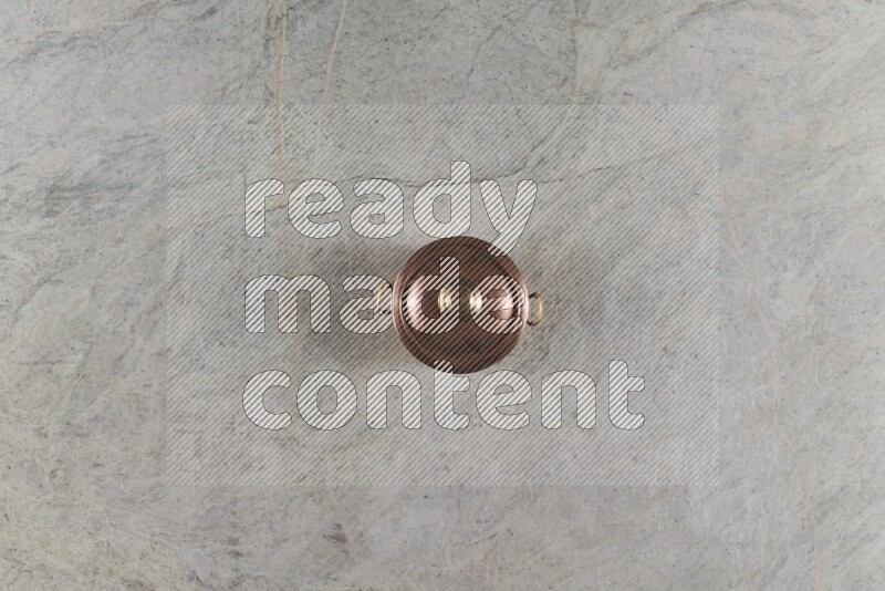 A small copper pot on grey marble background