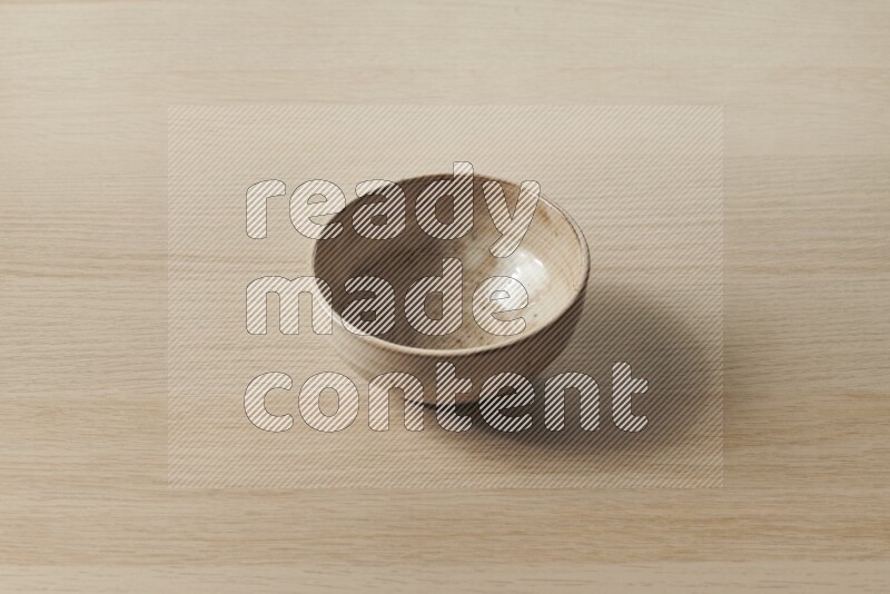 A beige pottery bowl on light wooden background