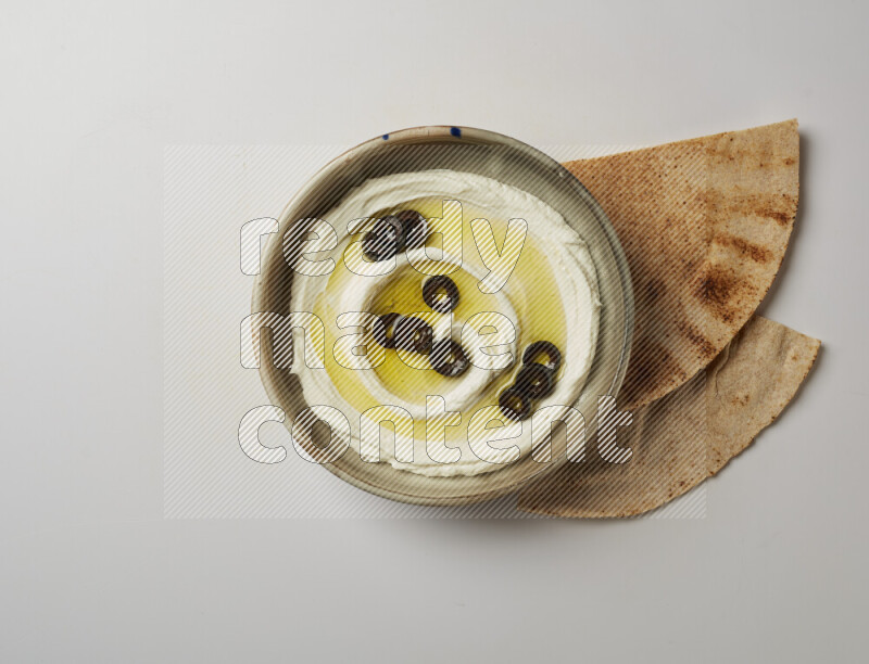 Lebnah garnished with sliced olives in a grey pottery plate on a white background