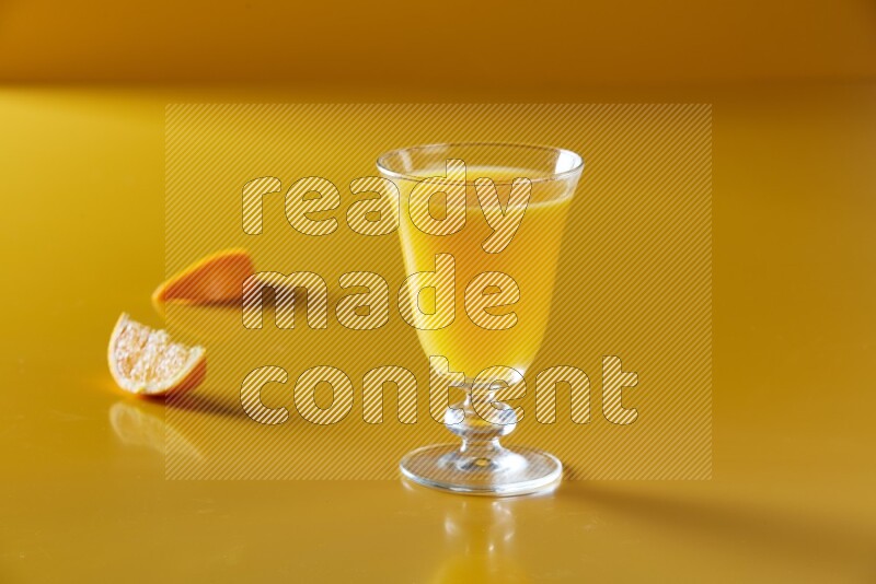 glass of orange juice on yellow background