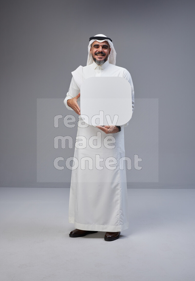 Saudi man Wearing Thob and white Shomag standing holding social media sign on Gray background