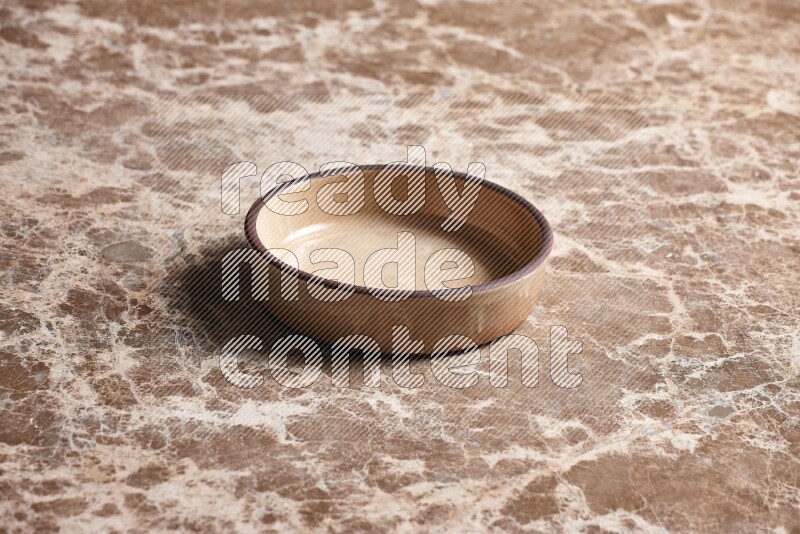 A beige pottery oven plate on beige marble background