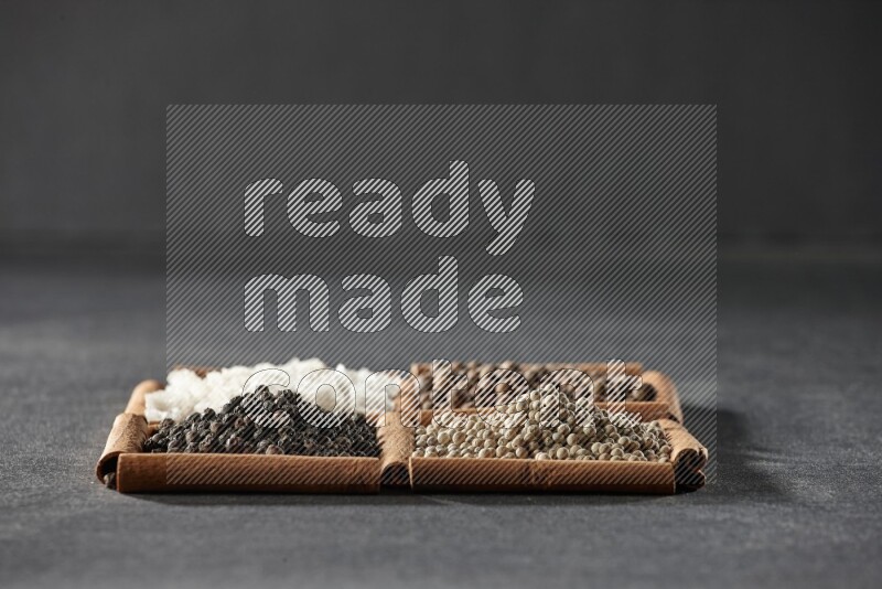 4 squares of cinnamon sticks full of black pepper, white pepper, allspice and white salt on black flooring