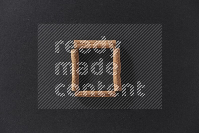 A single square of cinnamon sticks on black flooring