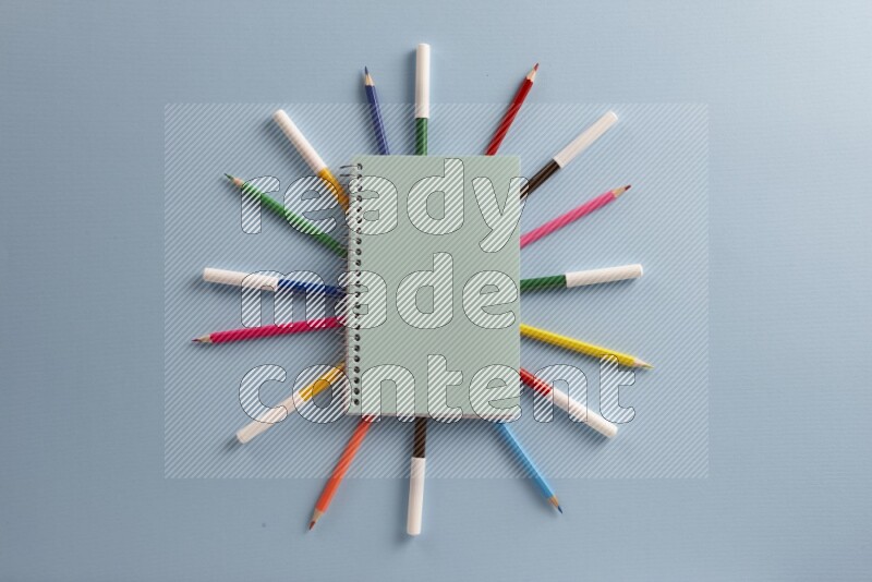 A blue notebook with different school supplies on blue background