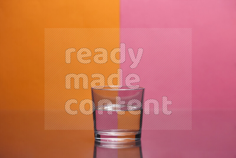 The image features a clear glassware filled with water, set against orange and pink background