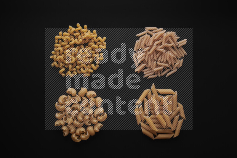 Different pasta types in bunches on black background