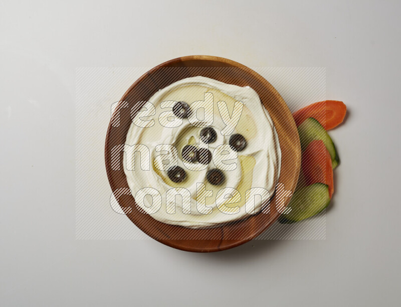 Lebnah garnished with sliced olives in a wooden plate on a white background