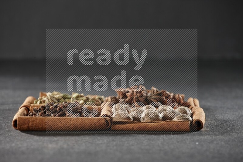 4 squares of cinnamon sticks full of cardamom, star anise, nutmegs and cloves on black flooring