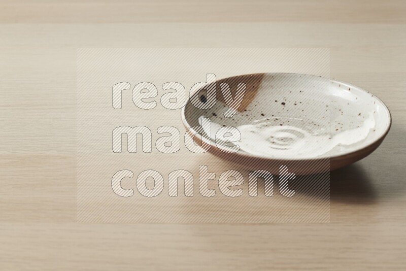 A multicolored pottery plate on light wooden background
