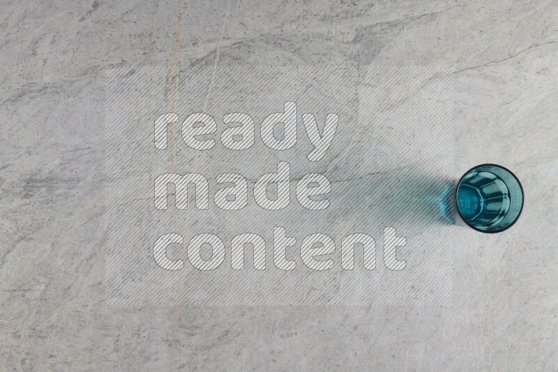 A turquoise glass cup on grey marble background