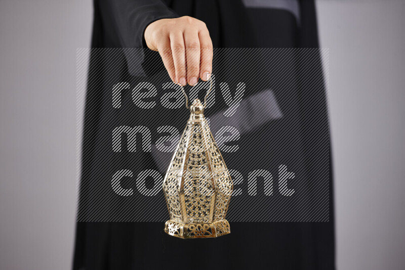 A woman in black abaya holding different ramadan lanterns in different positions