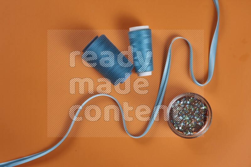 مجموعة من أدوات الخياطة والتفصيل زرقاء اللون على خلفية برتقالية