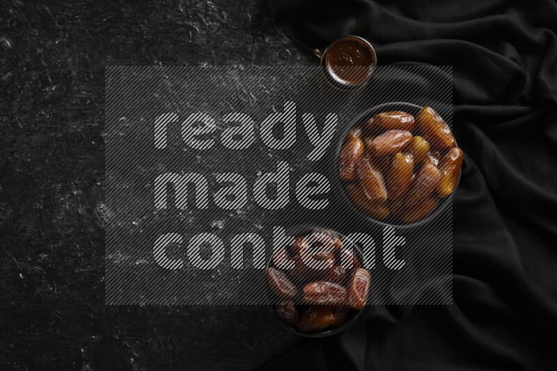 Dates in pottery bowls with coffee in a dark setup