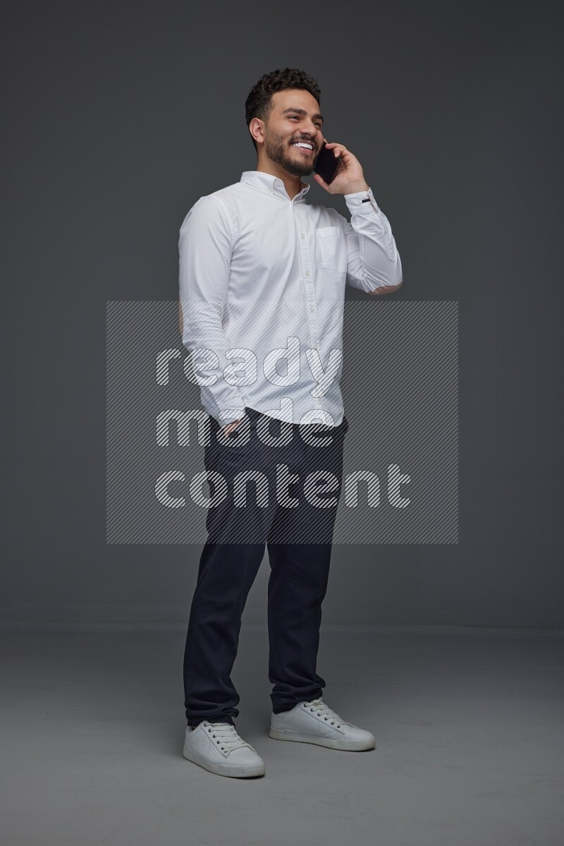 A man wearing smart casual talking in the phone eye level on a gray background