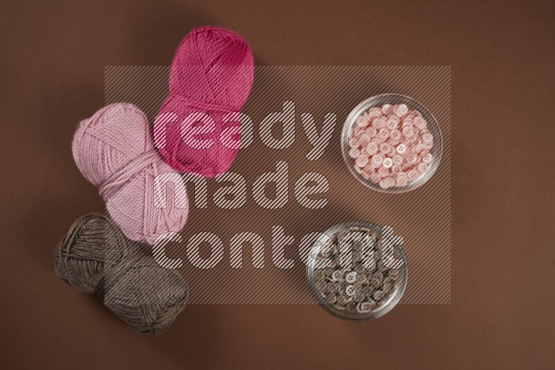 مجموعة من أدوات الخياطة والتفصيل زهرية اللون على خلفية بنية