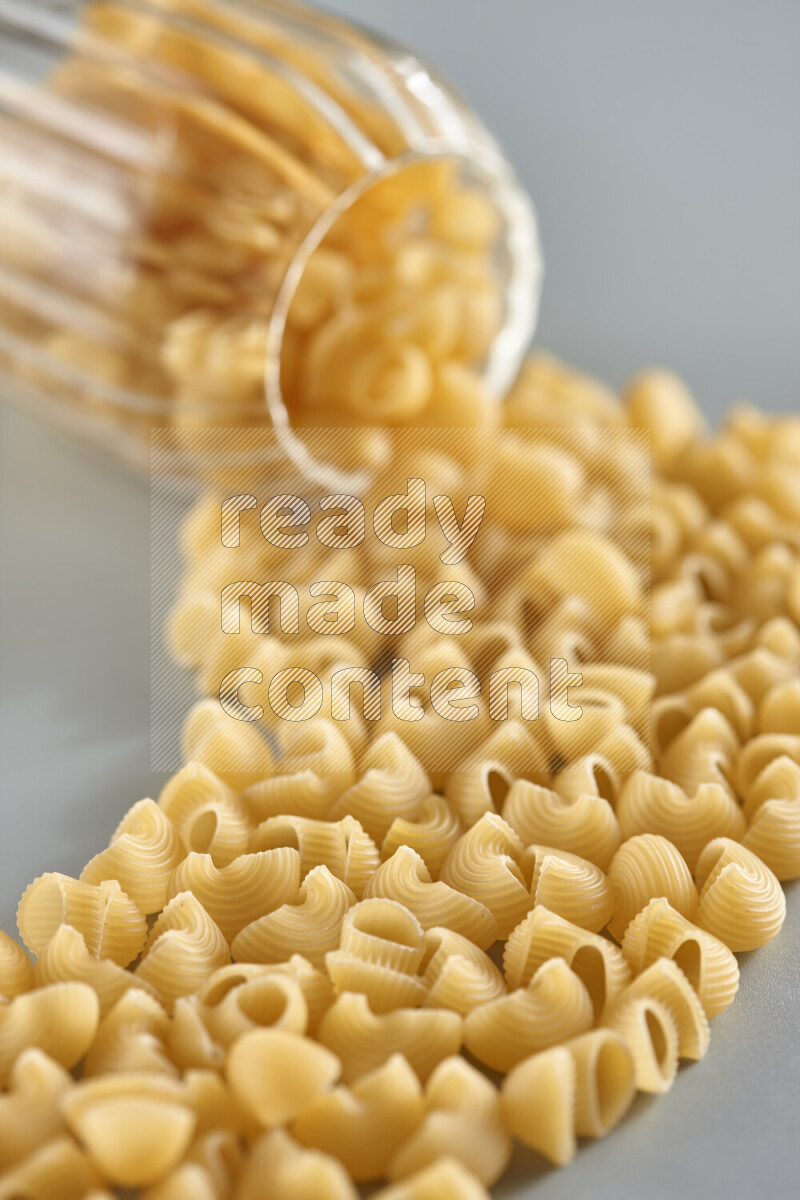 Flipped jar full of raw pasta on light blue background