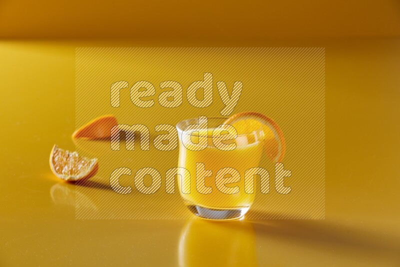glass of orange juice with orange slice on yellow background