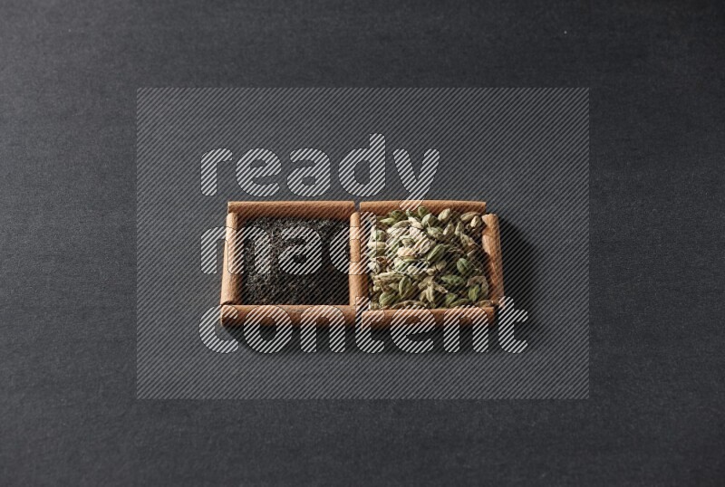 2 squares of cinnamon sticks full of cardamom and black tea on black flooring