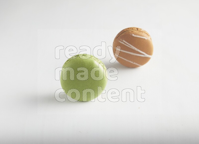 45º Shot of of two assorted Brown Irish Cream, and Green Pistachio macarons on white background