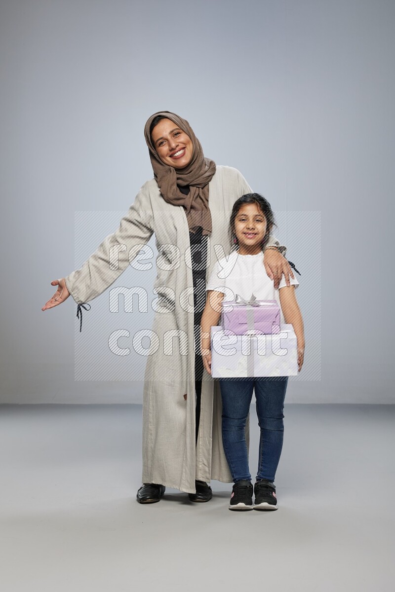 A girl giving a gift to her mother on gray background