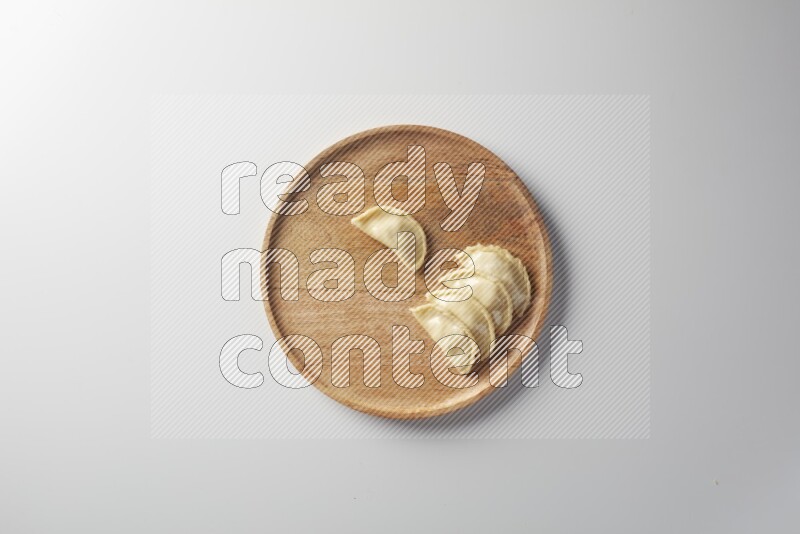 Five Sambosas on a wooden round plate on a white background