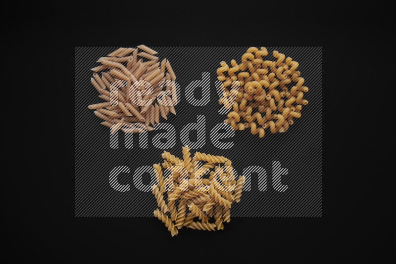 Different pasta types in bunches on black background