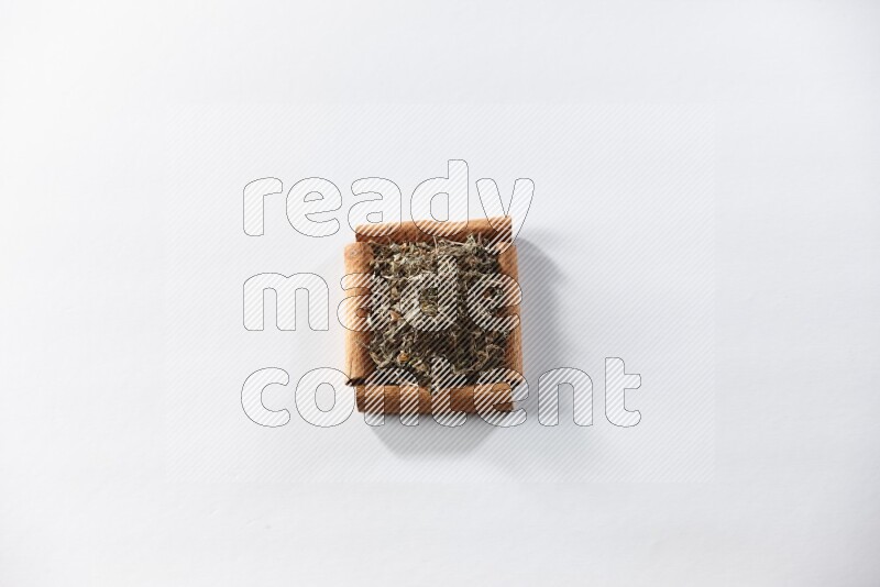 أربعة من أعواد القرفة مكونة شكل مربع بداخلها ريحان مجفف علي خلفية بيضاء