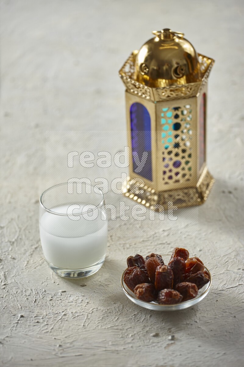A golden lantern with different drinks, dates, nuts, prayer beads and quran on textured white background