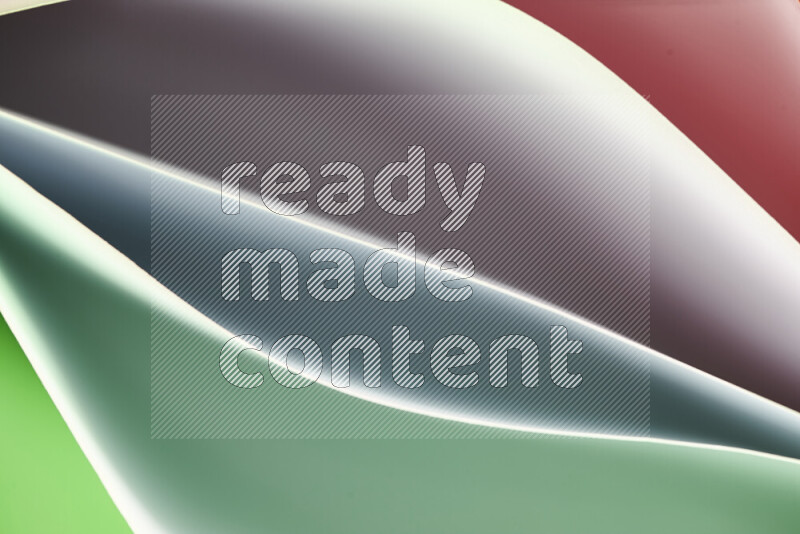 هذه الصورة تعرض تكوين فن الورق التجريدي مع منحنيات ورقية بتدرجات اللون الأخضر والأحمر المكونه بواسطة الضوء الملون