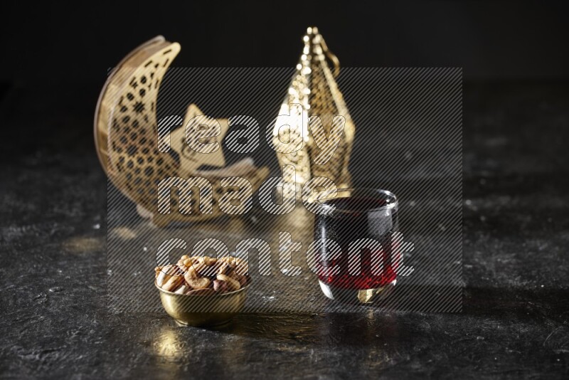 Nuts in a metal bowl with Hibiscus beside golden lanterns in a dark setup