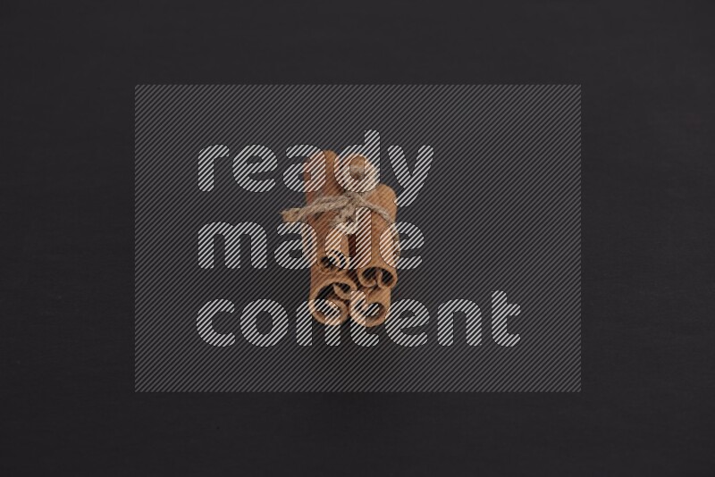 4 أعواد من القرفة مربوطة علي خلفية سوداء