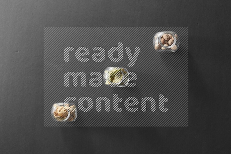 3 glass spice jars full of laurel bay leaves, ginger and nutmeg on black flooring