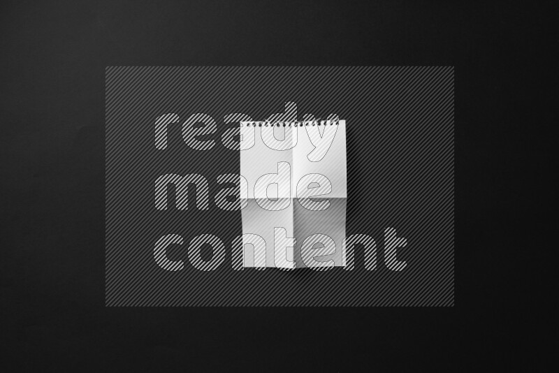 Folded notebook sheet on black background
