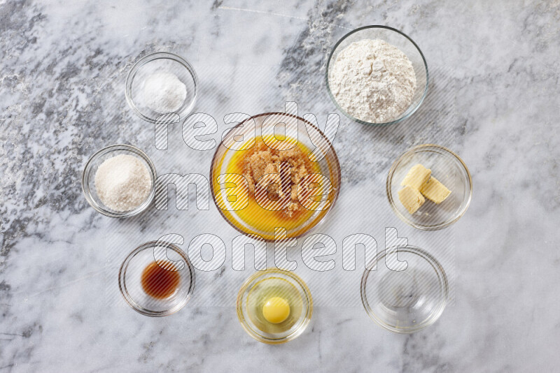 كوكيز خطوة بخطوة بمكوناتها، الدقيق، الزبدة، السكر البني، البيض، الفانيليا، السكر الأبيض، رقائق الشوكولاتة وصودا الخبز على خلفية رخام رمادي