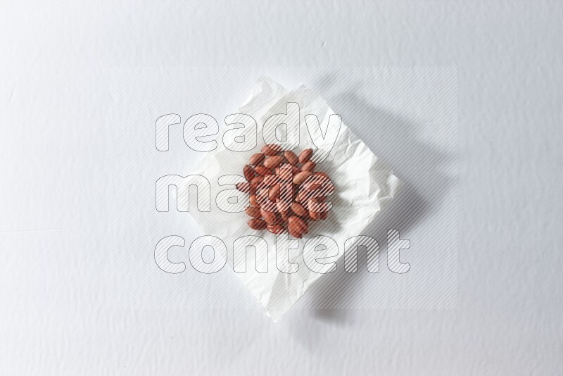 Red skin peanuts on a crumpled piece of paper on a white background in different angles